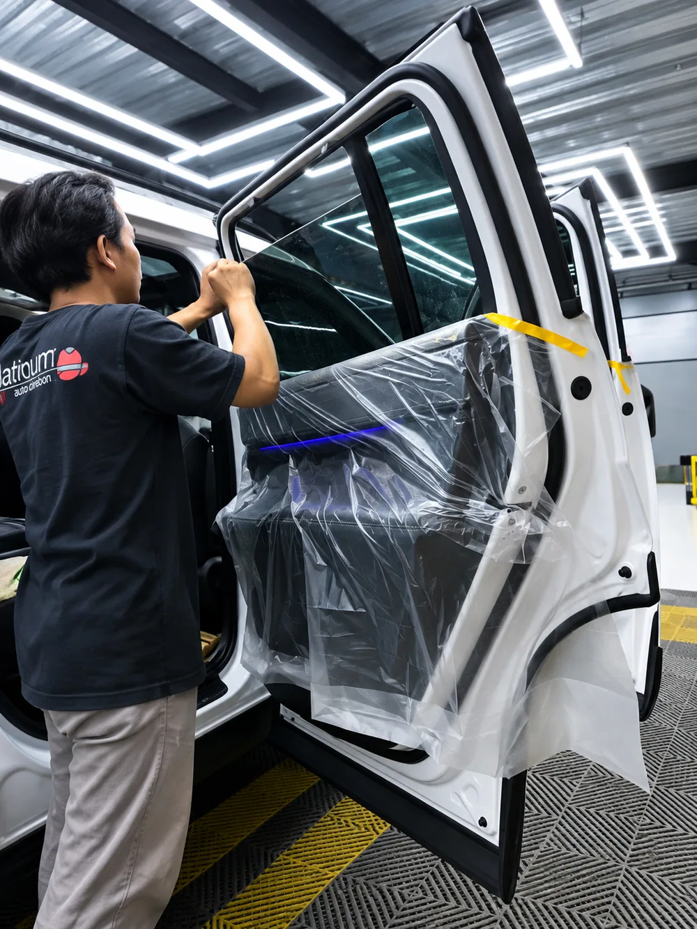 Teknisi memasang kaca film pada pintu mobil di Platinum Auto Center